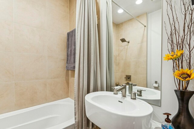 bathroom with recessed lighting, shower / tub combo with curtain, and a sink