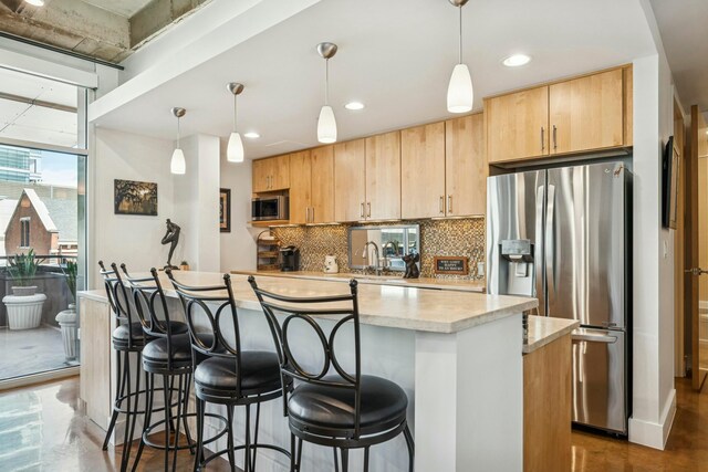 kitchen featuring a breakfast bar area, decorative backsplash, stainless steel appliances, a kitchen island, and light brown cabinetry