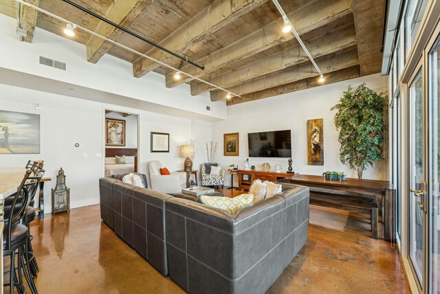 living room with concrete flooring, rail lighting, and visible vents