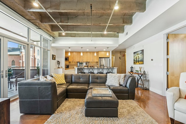 living area with track lighting, visible vents, and a high ceiling
