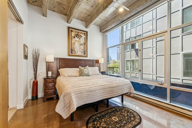bedroom with a baseboard heating unit, concrete flooring, and baseboards