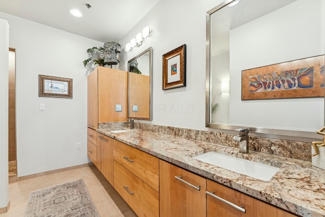 full bath with double vanity, baseboards, tile patterned flooring, and a sink