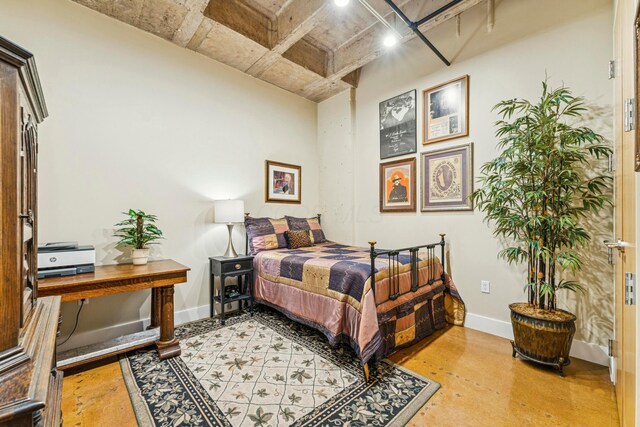 bedroom with concrete flooring and baseboards