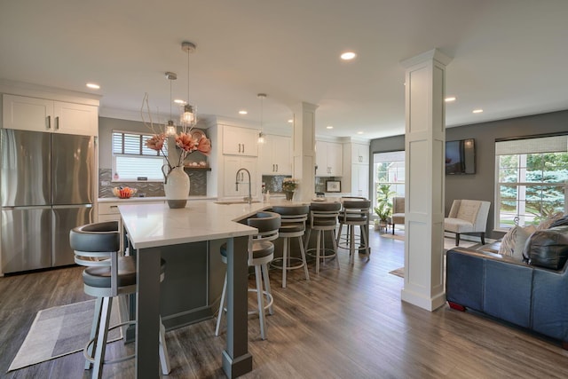 kitchen with plenty of natural light, a sink, freestanding refrigerator, and ornate columns