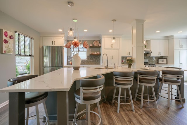kitchen with freestanding refrigerator, white cabinets, decorative backsplash, and a sink