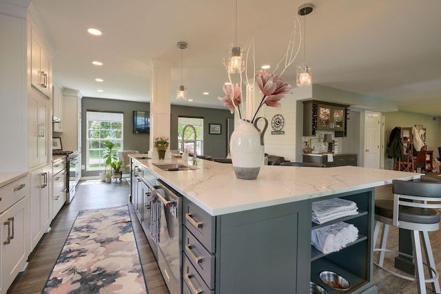 kitchen featuring recessed lighting, light stone countertops, a sink, stainless steel appliances, and white cabinets