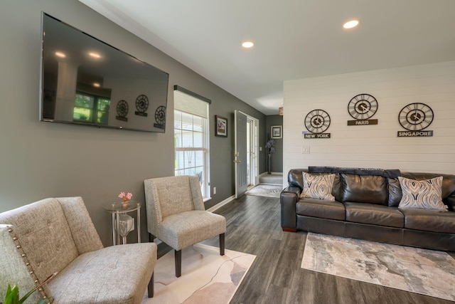 living room featuring wood walls, dark wood-style flooring, recessed lighting, and baseboards