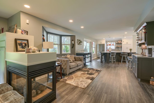 living room featuring recessed lighting, a notable chandelier, and dark wood-style floors