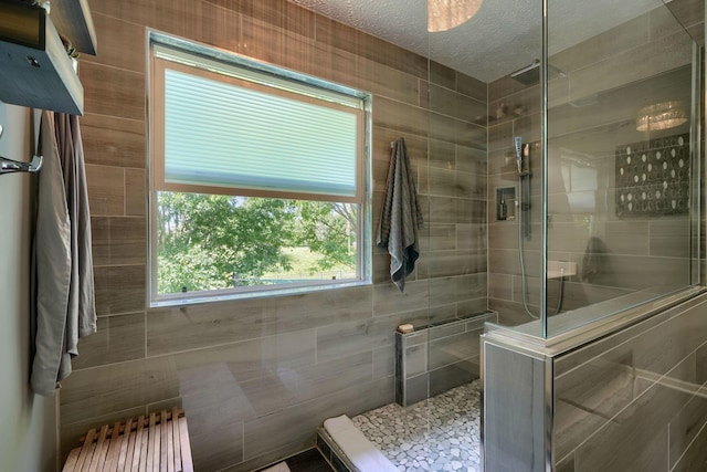 bathroom with a textured ceiling and tiled shower