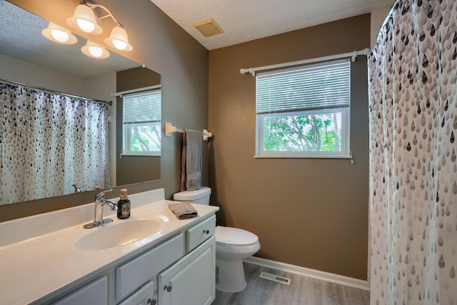 bathroom featuring toilet, vanity, visible vents, and wood finished floors