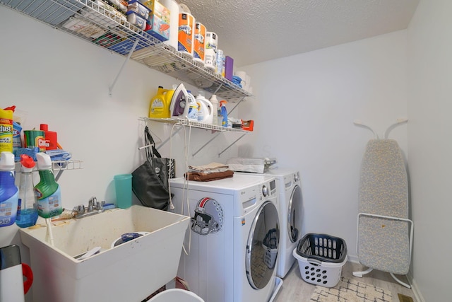 washroom featuring baseboards, a sink, laundry area, and independent washer and dryer