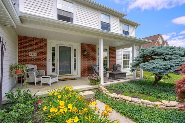 entrance to property with covered porch, outdoor lounge area, and brick siding