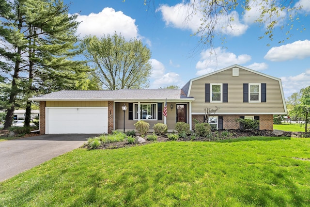 tri-level home featuring a garage, driveway, brick siding, and a front yard
