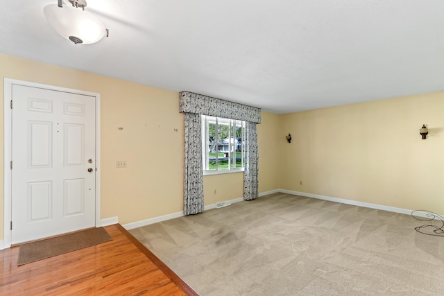 spare room with baseboards and light colored carpet