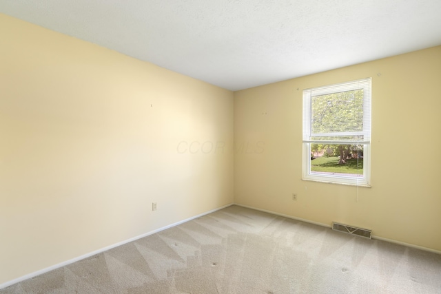 unfurnished room with light carpet and baseboards