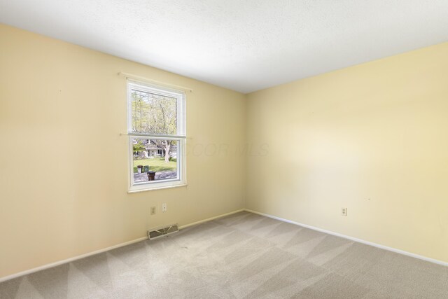 empty room featuring light carpet and baseboards