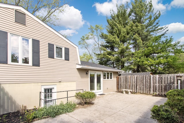 rear view of house with fence, a patio area, and roof with shingles