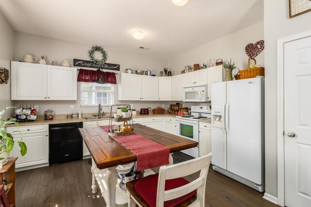 kitchen with white cabinets, a sink, dark wood finished floors, white appliances, and light countertops
