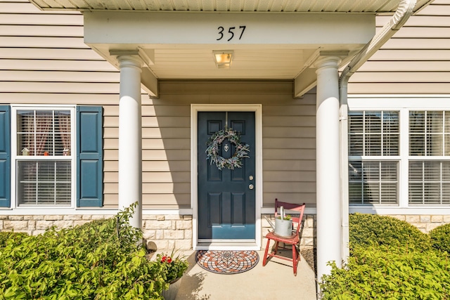 doorway to property with a porch and stone siding