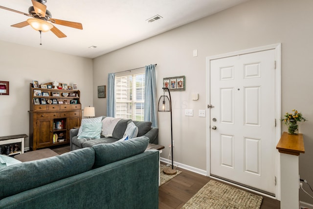 living room featuring ceiling fan, visible vents, baseboards, and dark wood-style flooring