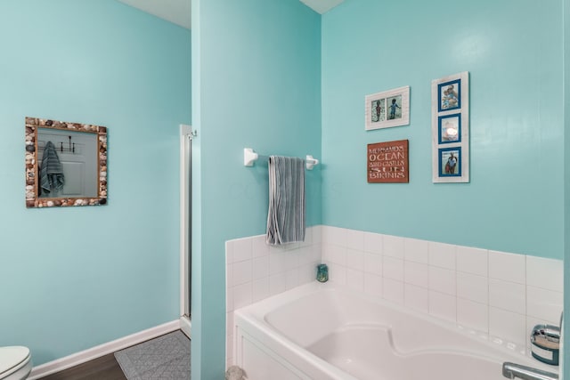 bathroom with a bath, toilet, and baseboards