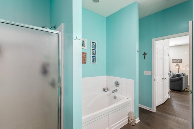 full bathroom with baseboards, a garden tub, wood finished floors, and a shower stall