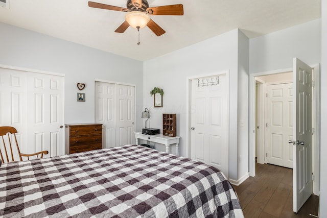 bedroom with two closets, a ceiling fan, baseboards, and dark wood-style flooring