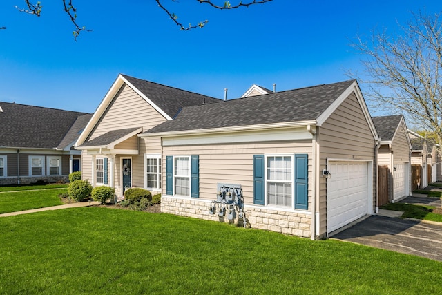 view of front of house featuring a garage, a shingled roof, a front yard, and aphalt driveway