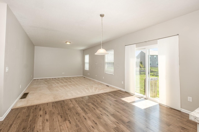unfurnished dining area featuring baseboards, wood finished floors, and visible vents
