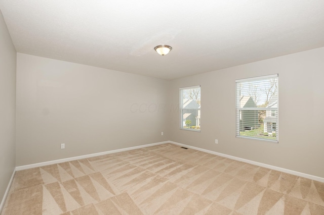spare room featuring baseboards and light carpet