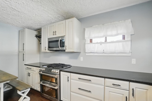 kitchen featuring white cabinets, stainless steel appliances, a textured ceiling, and dark countertops