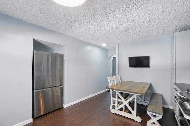 interior space featuring arched walkways, baseboards, a textured ceiling, and dark wood-style flooring