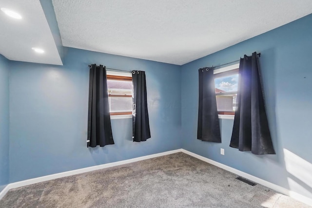 unfurnished room featuring carpet floors, a healthy amount of sunlight, visible vents, and baseboards