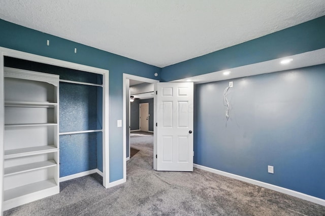 unfurnished bedroom featuring a textured ceiling, carpet, a closet, and baseboards