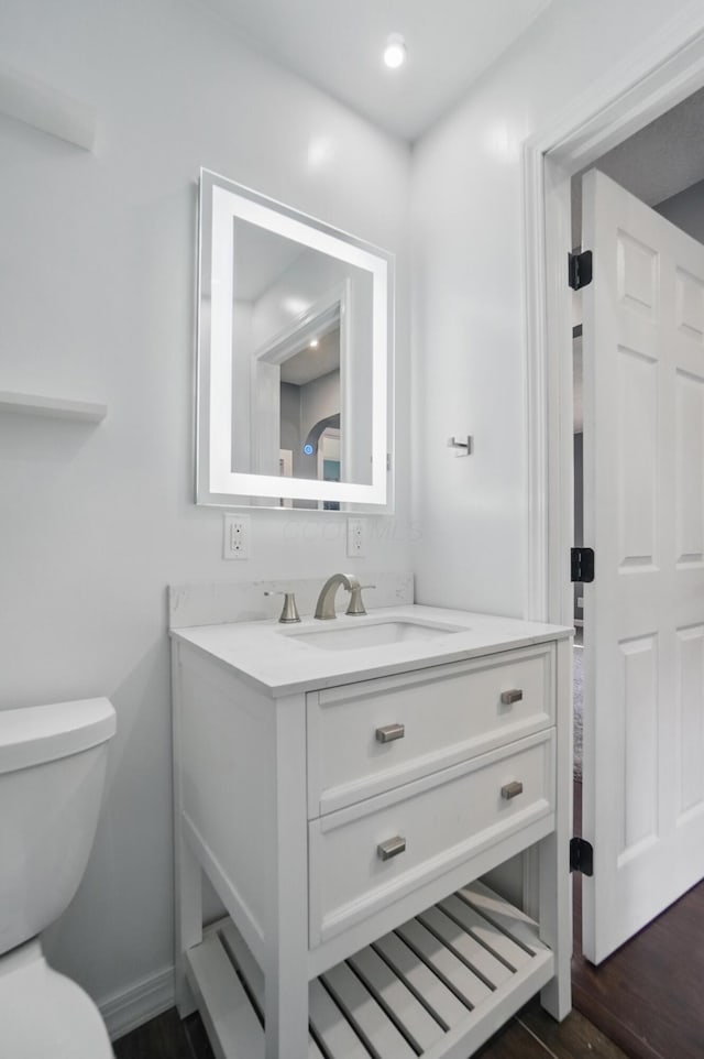 bathroom with recessed lighting, wood finished floors, toilet, and vanity