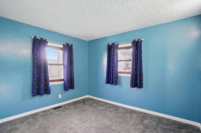 empty room with baseboards, carpet flooring, a textured ceiling, and visible vents