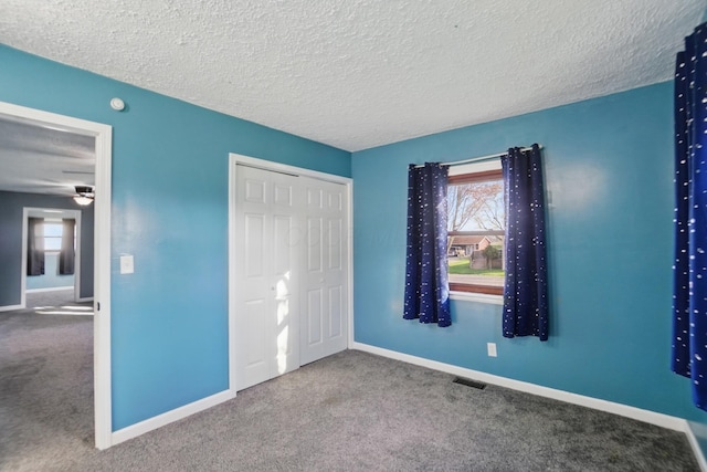 unfurnished bedroom featuring carpet floors, a textured ceiling, visible vents, and baseboards