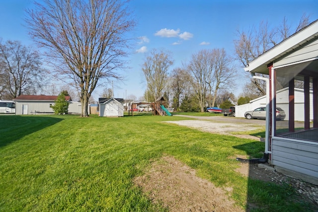view of yard with a storage shed, an outbuilding, and a playground