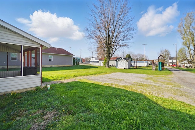 view of yard with an outdoor structure, a sunroom, a storage unit, and a playground