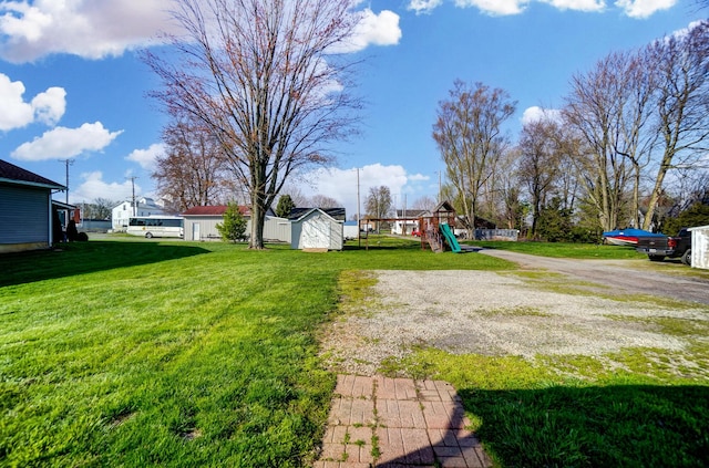 view of yard with an outbuilding, a shed, and a playground