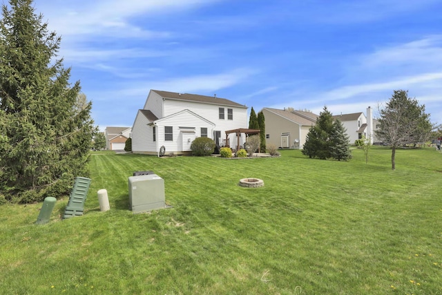 back of property with a fire pit and a lawn