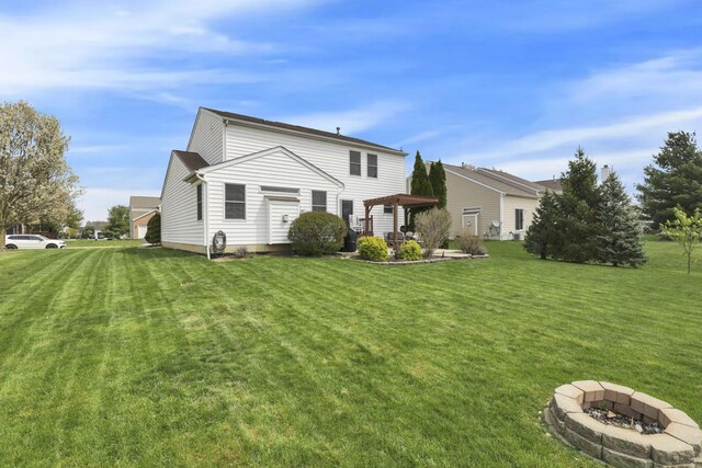 rear view of house with a lawn, a pergola, and an outdoor fire pit
