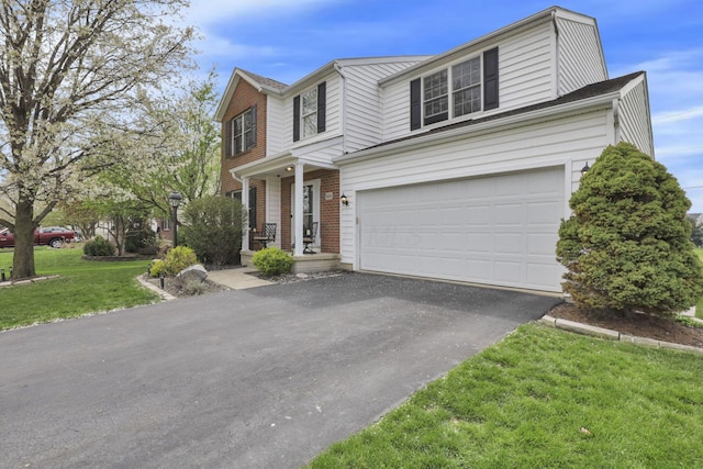 traditional home featuring brick siding, driveway, a front lawn, and a garage
