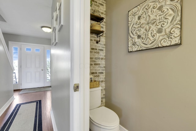 bathroom featuring baseboards, wood finished floors, and toilet