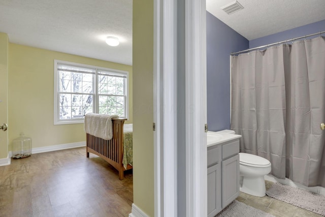 bathroom featuring toilet, vanity, a textured ceiling, and visible vents