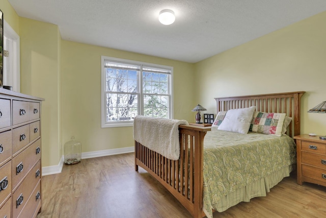 bedroom featuring baseboards, a textured ceiling, and light wood-style flooring