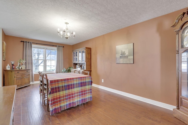 dining room featuring baseboards, wood finished floors, a chandelier, and a healthy amount of sunlight