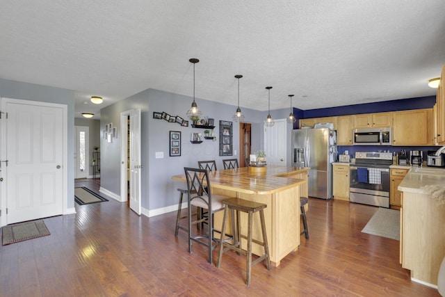 kitchen featuring stainless steel appliances, baseboards, light brown cabinetry, and dark wood-style flooring