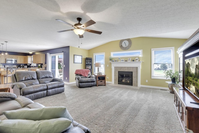 living area with lofted ceiling, a tiled fireplace, baseboards, and ceiling fan