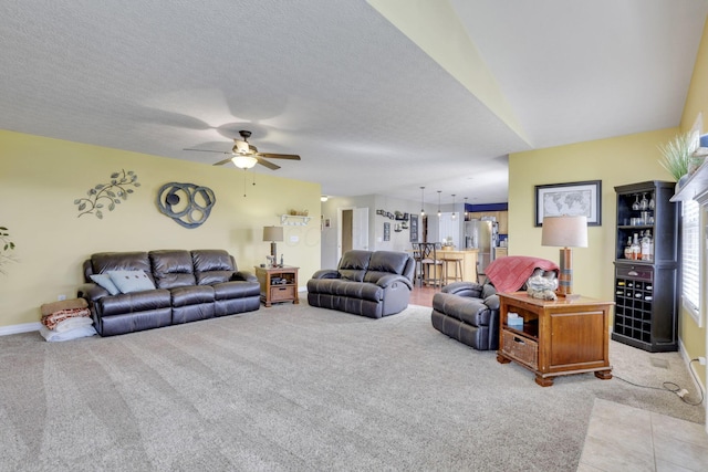 living area featuring ceiling fan, baseboards, and light colored carpet